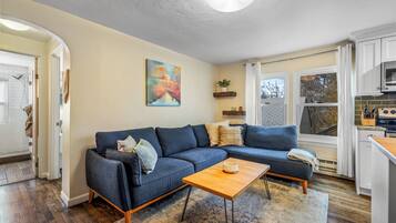 Un salon moderne avec un canapé d’angle, une table basse et un tableau accroché au mur.