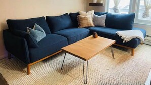 Ein Wohnzimmer mit einem dunkelblauen Sofa, einem Holztisch und einem großen Spiegel an der Wand.