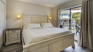 A bedroom with a large bed, bedside lamps, a nightstand, and a balcony with a view of the outside. - Ocean Views, Balcony, Pool, STEPS to Beach, Restaurants, Shops (Wrightsville Beach)