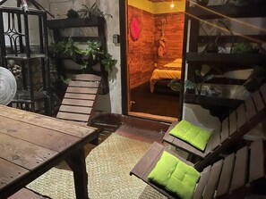 Relax in a serene outdoor seating area surrounded by lush plants and a wooden staircase.