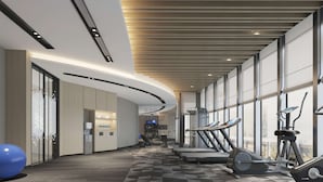 A modern gym with exercise equipment, large windows, and a checkered floor. - Hilton Garden Inn Anshan Haicheng (Anshan)
