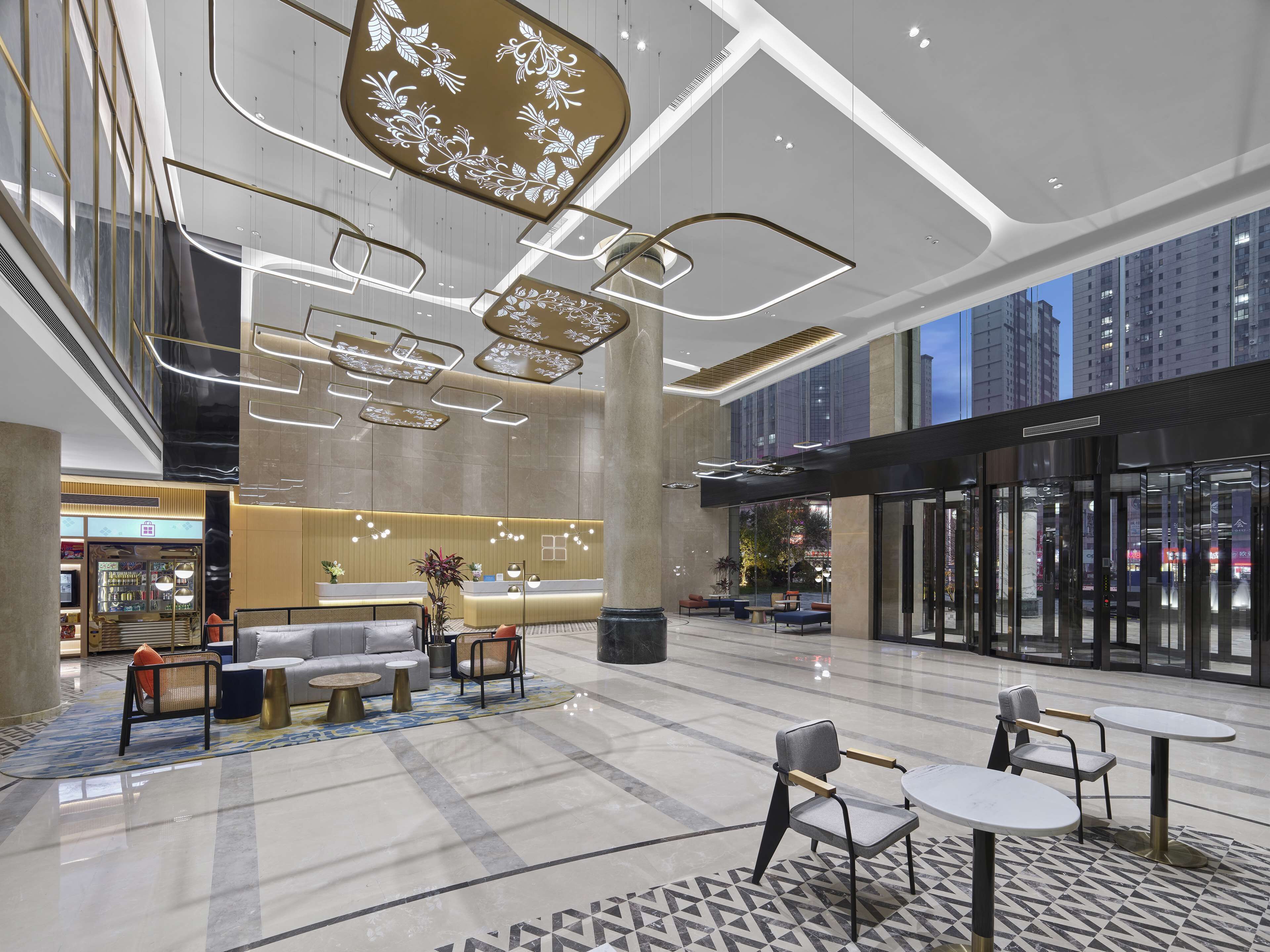 A modern lobby with a reception desk, seating area, and a glass entrance.