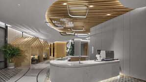 A modern reception area with a curved reception desk, a coffee machine, and a seating area with plants. - Hilton Garden Inn Anshan Haicheng (Anshan)