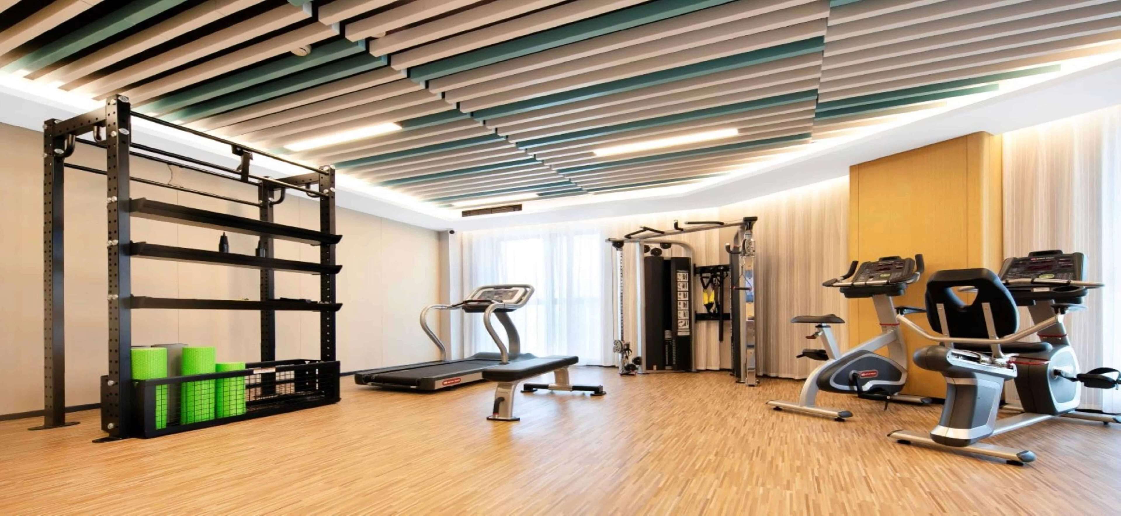 A gym with a treadmill, elliptical, weight machines, and a pull-up bar.