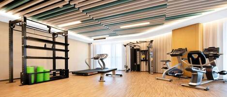 A gym with a treadmill, elliptical, weight machines, and a pull-up bar.