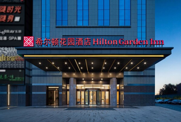 The exterior of the Hilton Garden Inn with a modern design, featuring a prominent entrance with a revolving door, and signage in both English and Chinese. - Hilton Garden Inn Changsha Yuelu (Changsha)