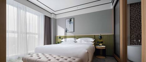 Una habitación de hotel moderna con una cama grande, un banco, una mesita de noche, una lámpara de pared y un baño con pared de azulejos.