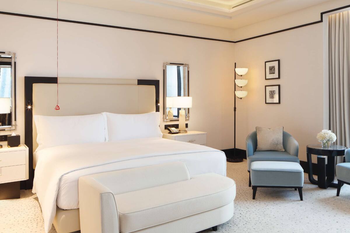 Une chambre d’hôtel avec un grand lit, une chaise, une petite table et une table de chevet.