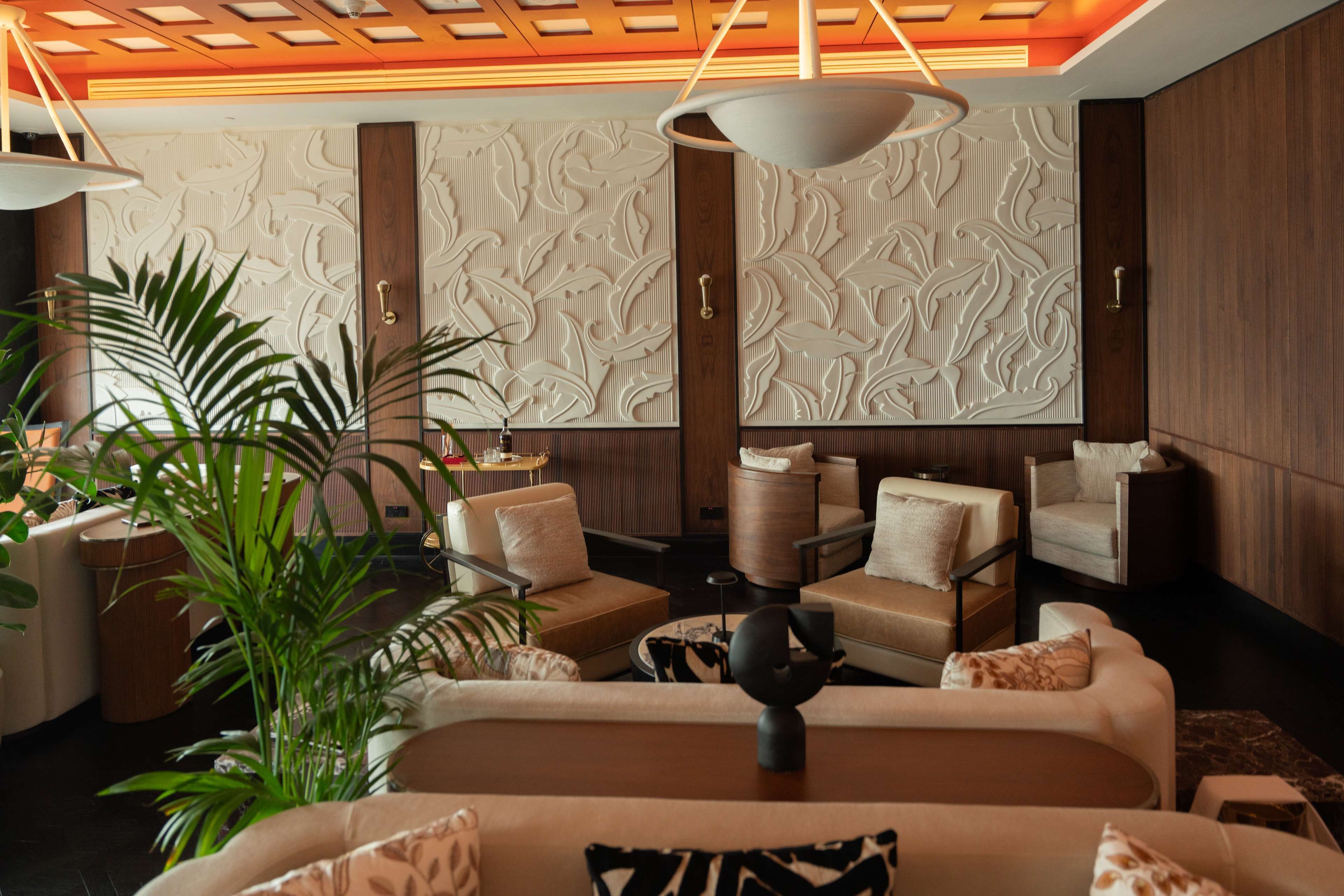 A modern living room with a sofa set, armchairs, a coffee table, and a decorative wall panel.