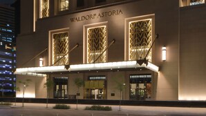 Un hotel de varios pisos con detalles arquitectónicos iluminados y una entrada destacada.