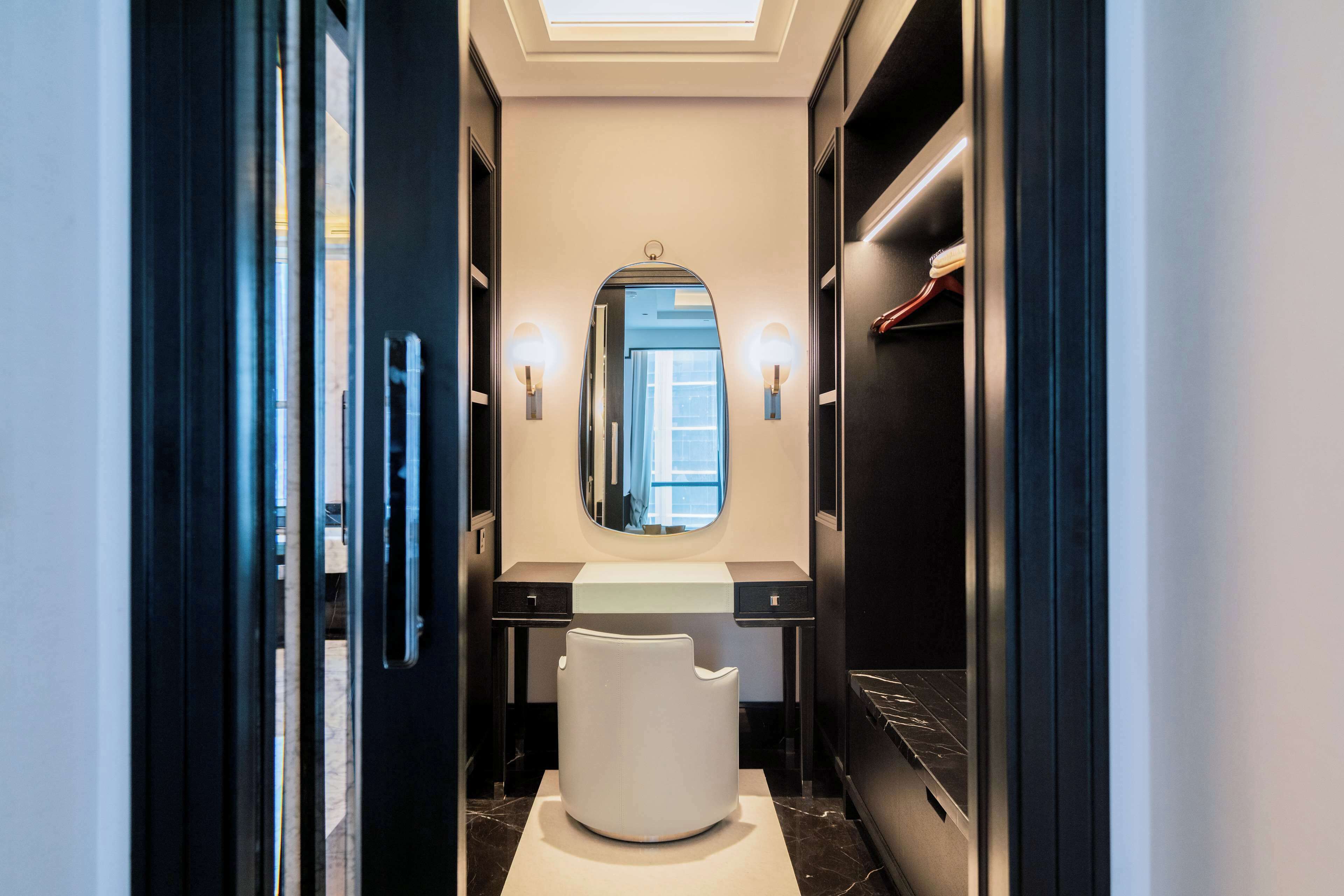 A modern bathroom with a vanity, a large mirror, and a white chair.