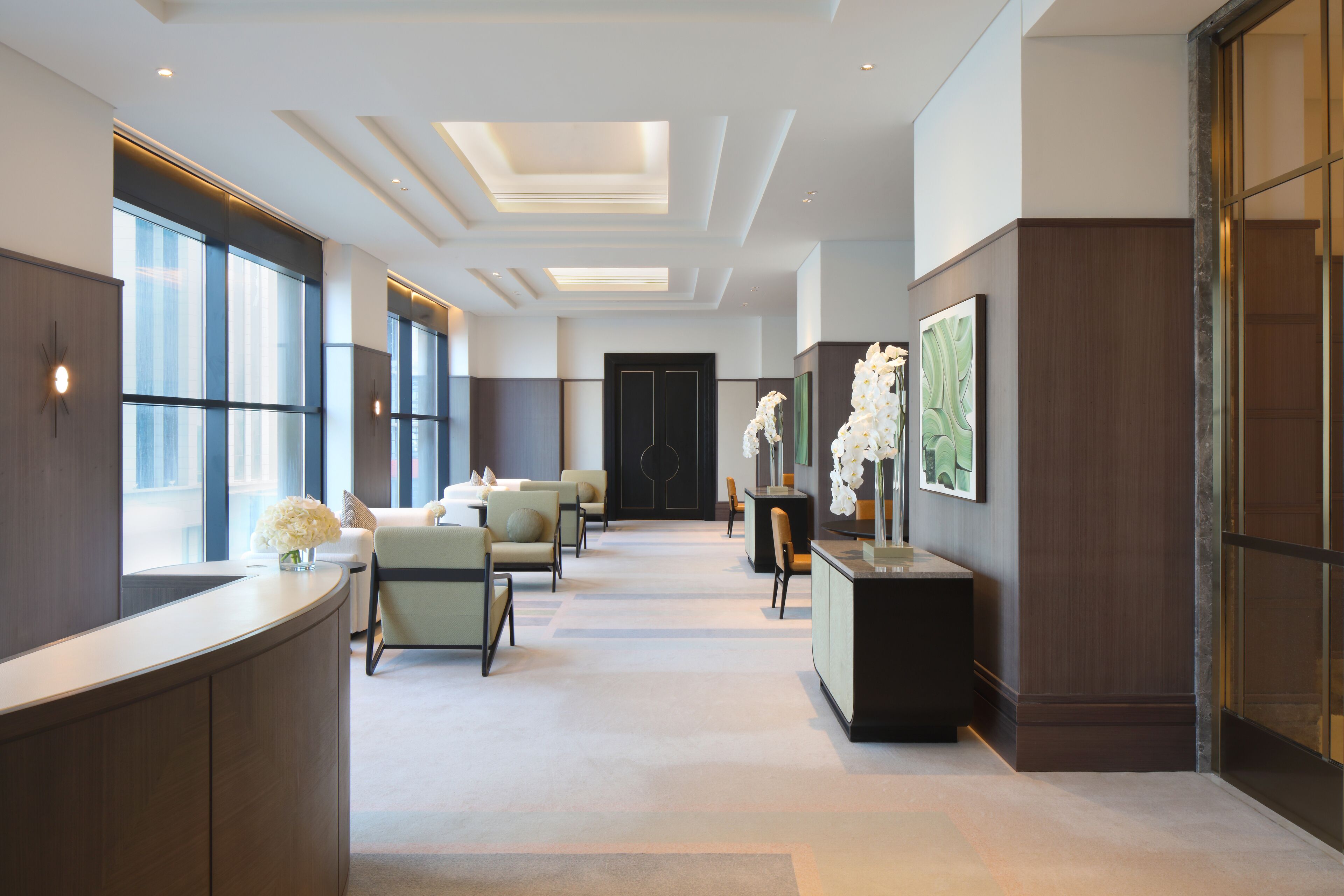 Un moderno vestíbulo de hotel con mostrador de recepción, área de descanso y obras de arte.