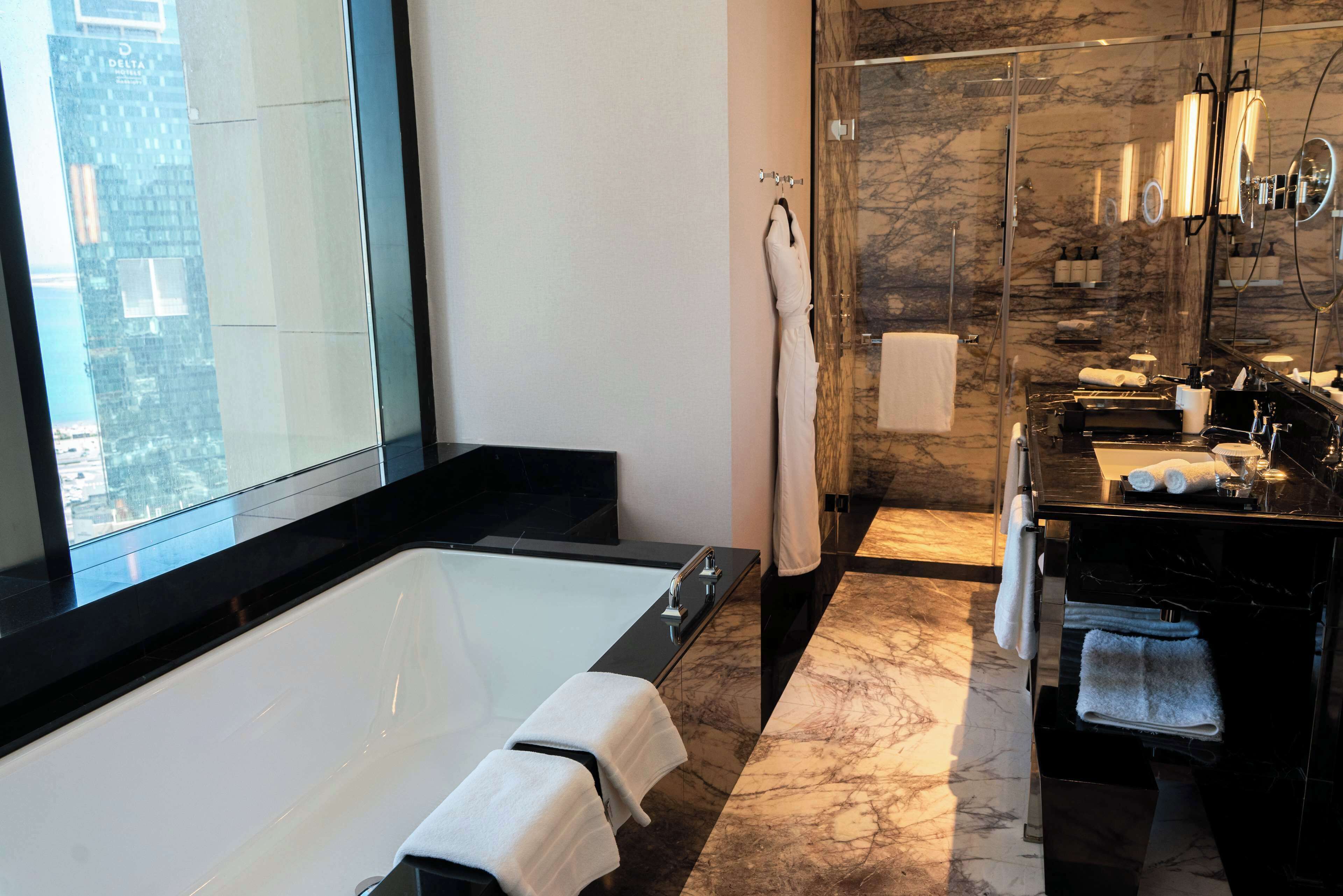 Un baño moderno con una bañera grande, cabina de ducha con vidrio y tocador con espejo.