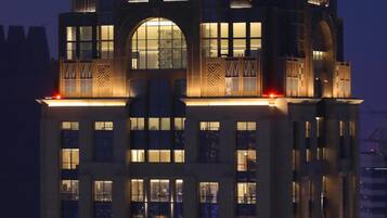 Un edificio de gran altura con un llamativo logotipo 'W' en la parte superior, múltiples ventanas iluminadas y un diseño arquitectónico moderno.