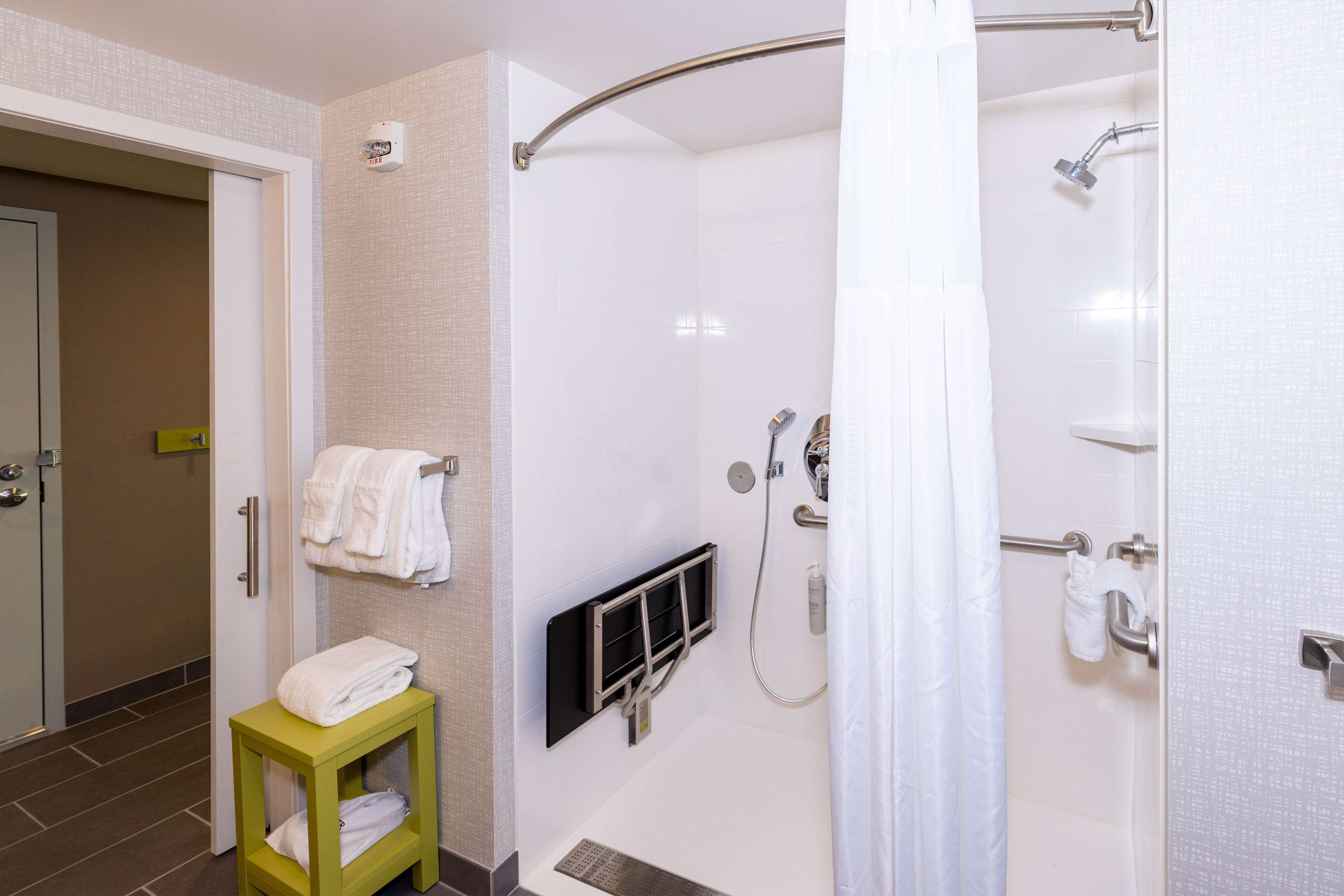 Une salle de bain moderne avec une douche à l’italienne, des toilettes et une petite table avec des serviettes.