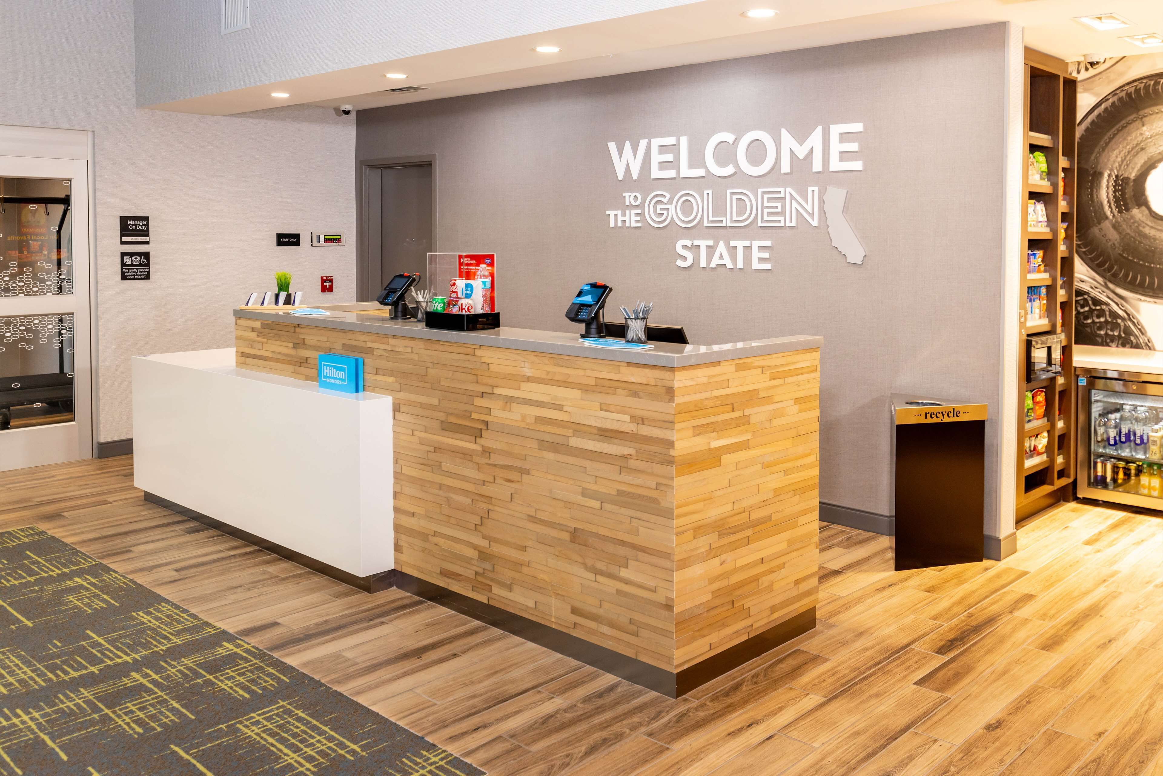 Un mostrador de recepción de hotel con detalles de madera, un cartel que dice 