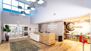 A modern reception area with a wooden reception desk, a 'Welcome to the Golden State' sign, and a snack bar with a variety of treats.
