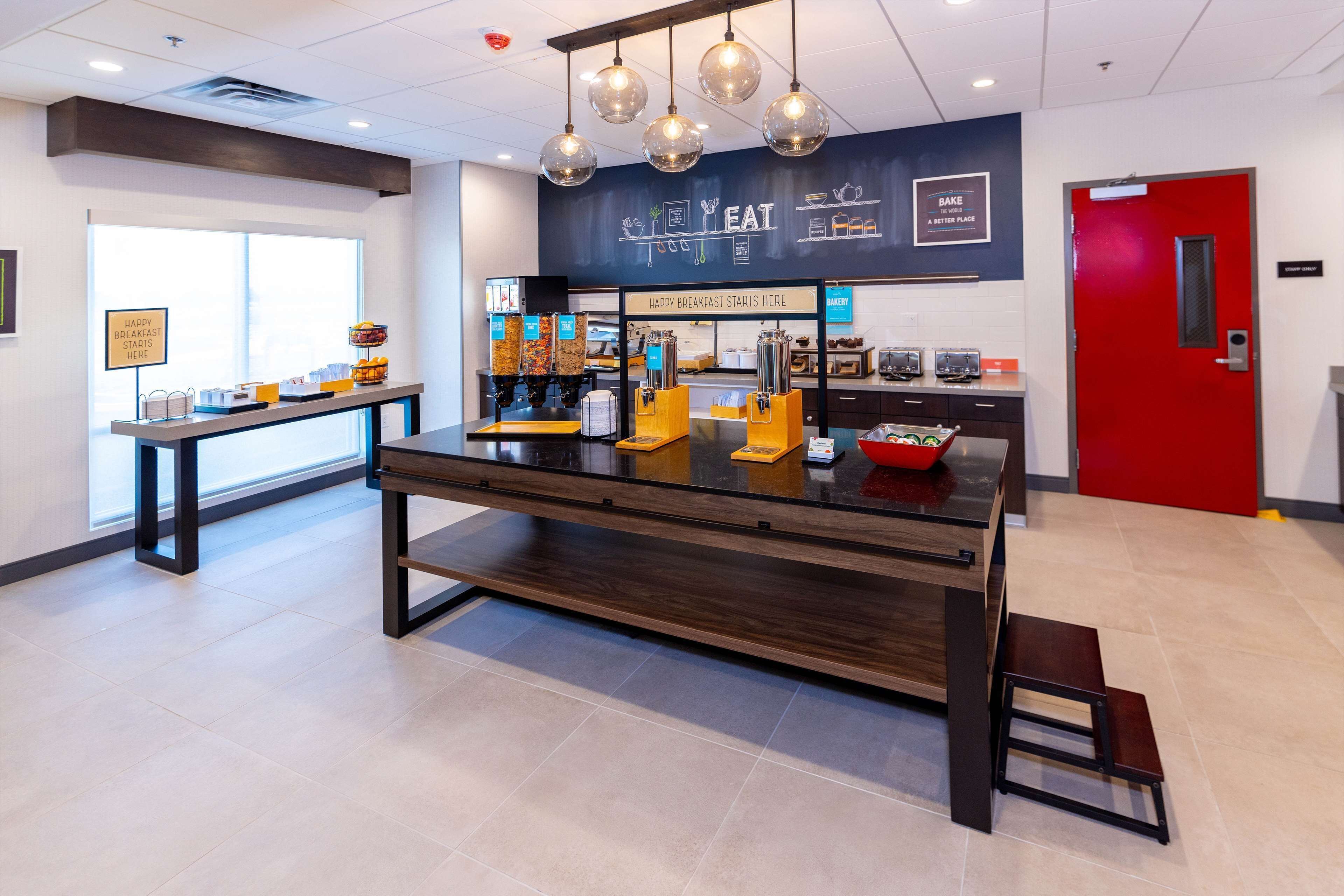 A modern breakfast area with a counter, seating, and a sign indicating breakfast services.