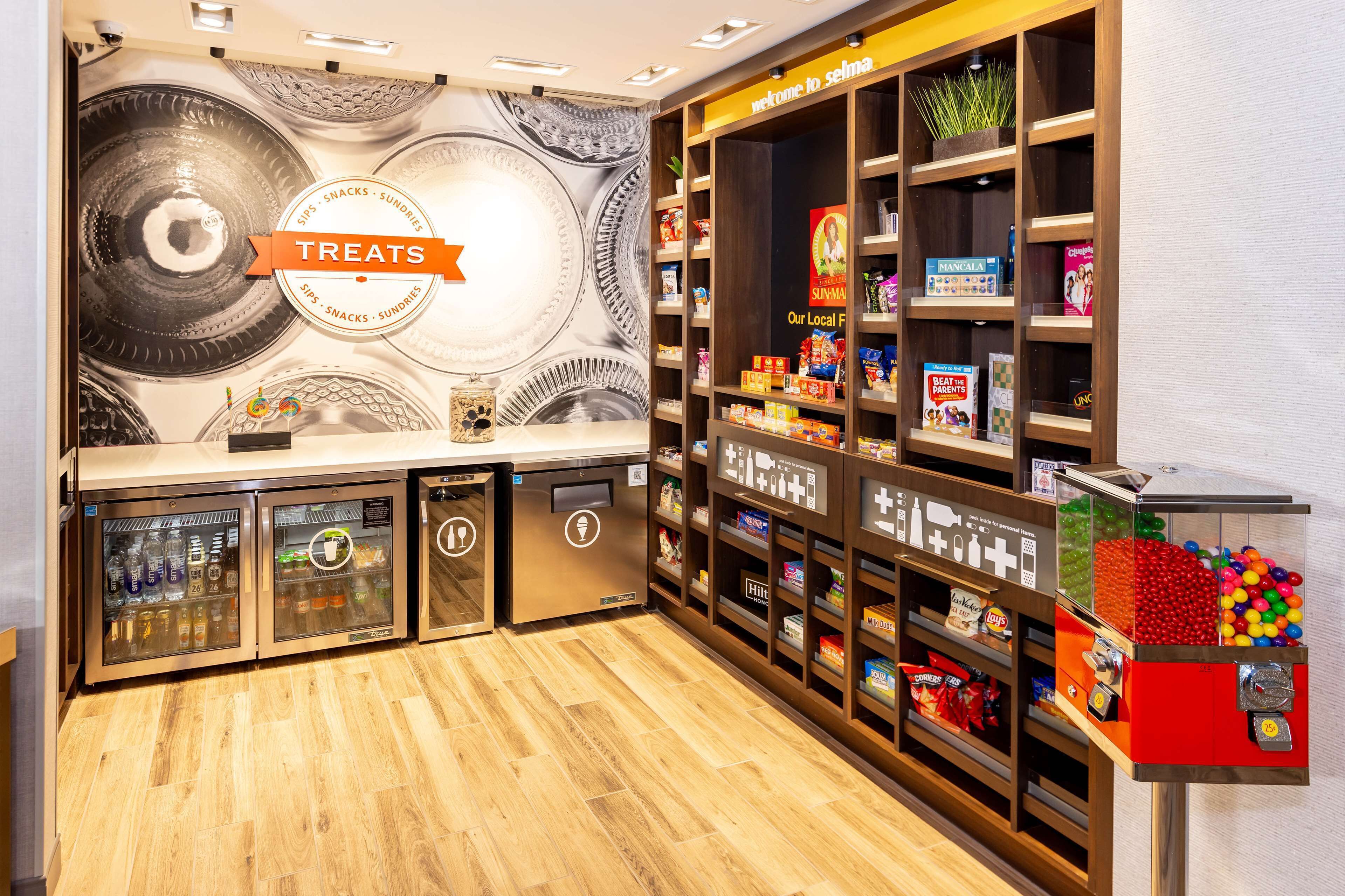 A snack bar with a 'Treats' sign, vending machines, and shelves stocked with snacks and drinks.