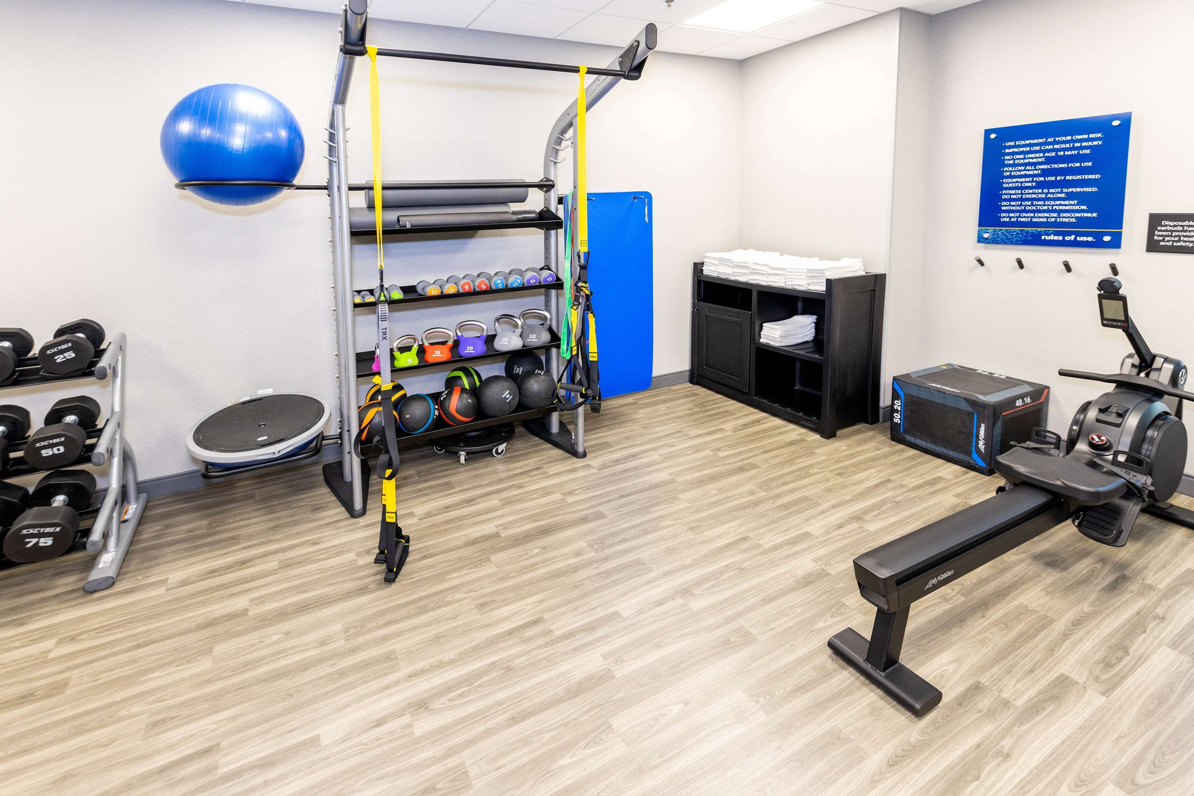 Un gimnasio con equipo de ejercicio, una pelota de ejercicio azul y un letrero en la pared.