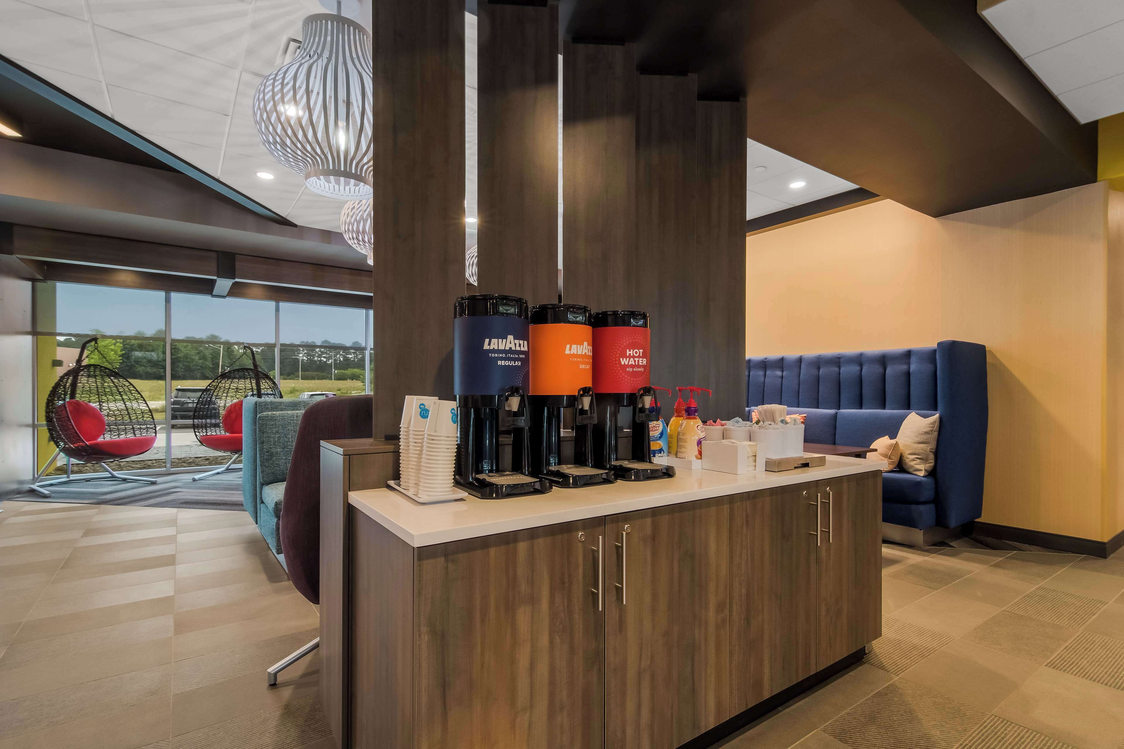 Zona de recepción con mostrador, máquinas de café y asientos.