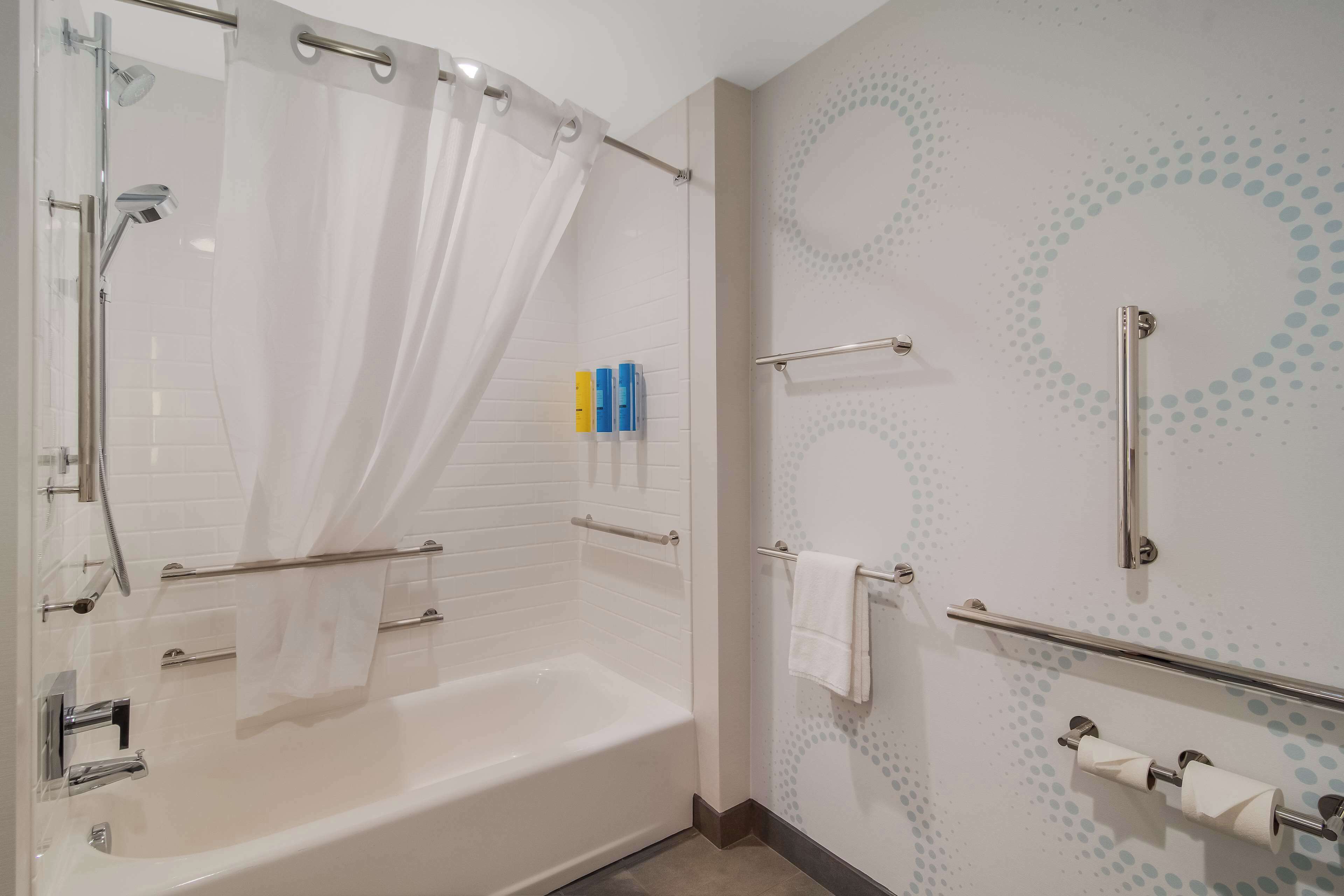 Un baño moderno con bañera, ducha y barras de apoyo.