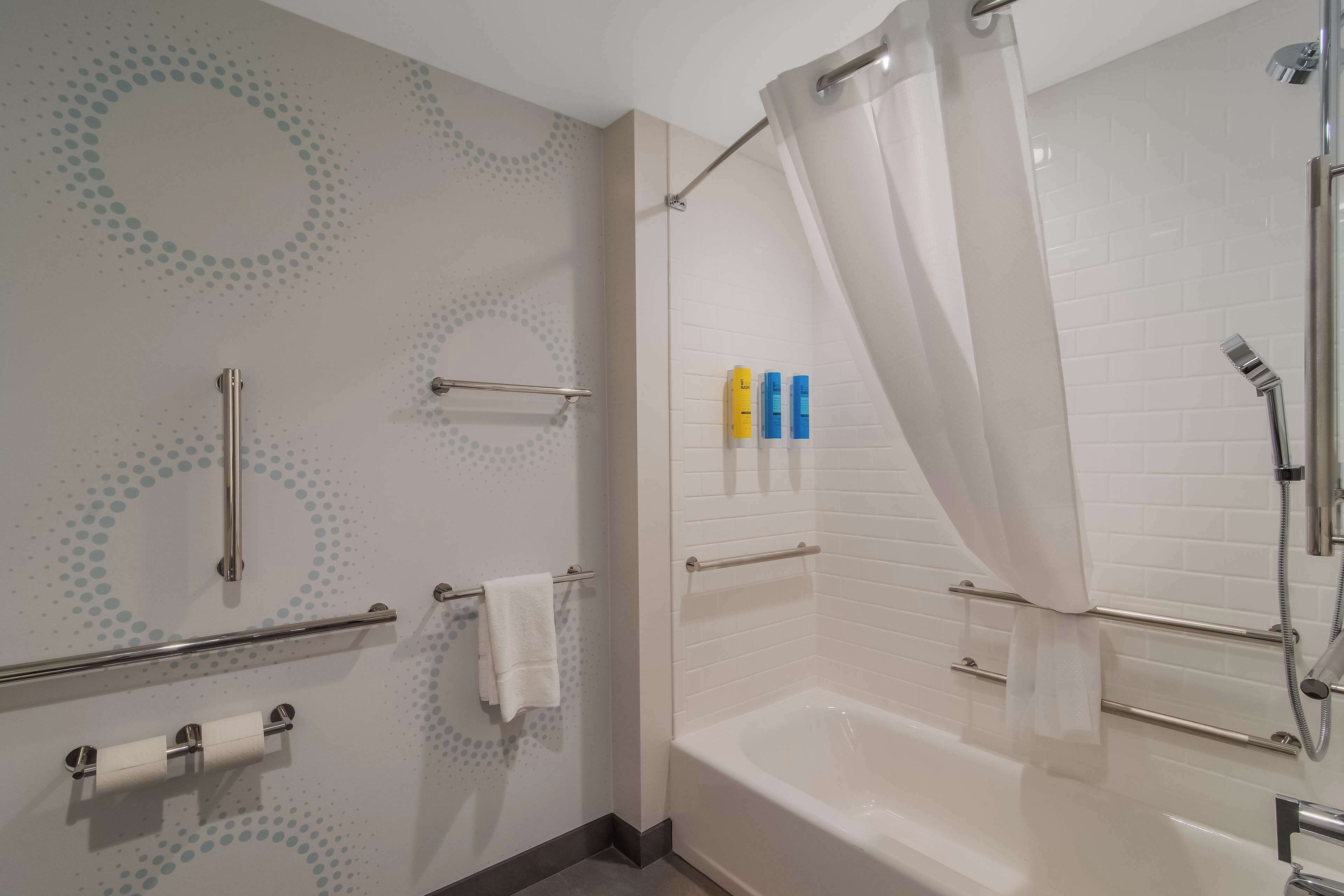 Un bagno moderno con vasca, doccia e porta carta igienica.