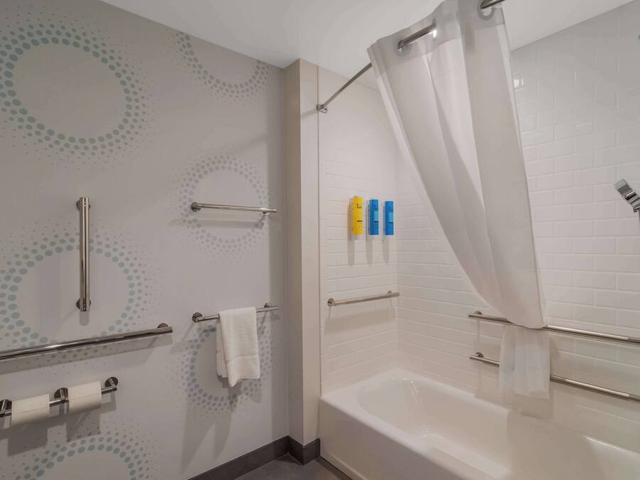 Un bagno moderno con vasca, doccia e porta carta igienica.