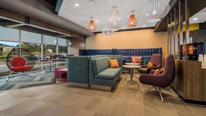 Een moderne hotellobby met een hoekbank, een ronde tafel en een bar.