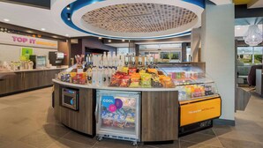 Een ontbijtruimte met een toonbank waarop snacks en drankjes staan, een koeltoog en een bordje met 'Top It Breakfast'.