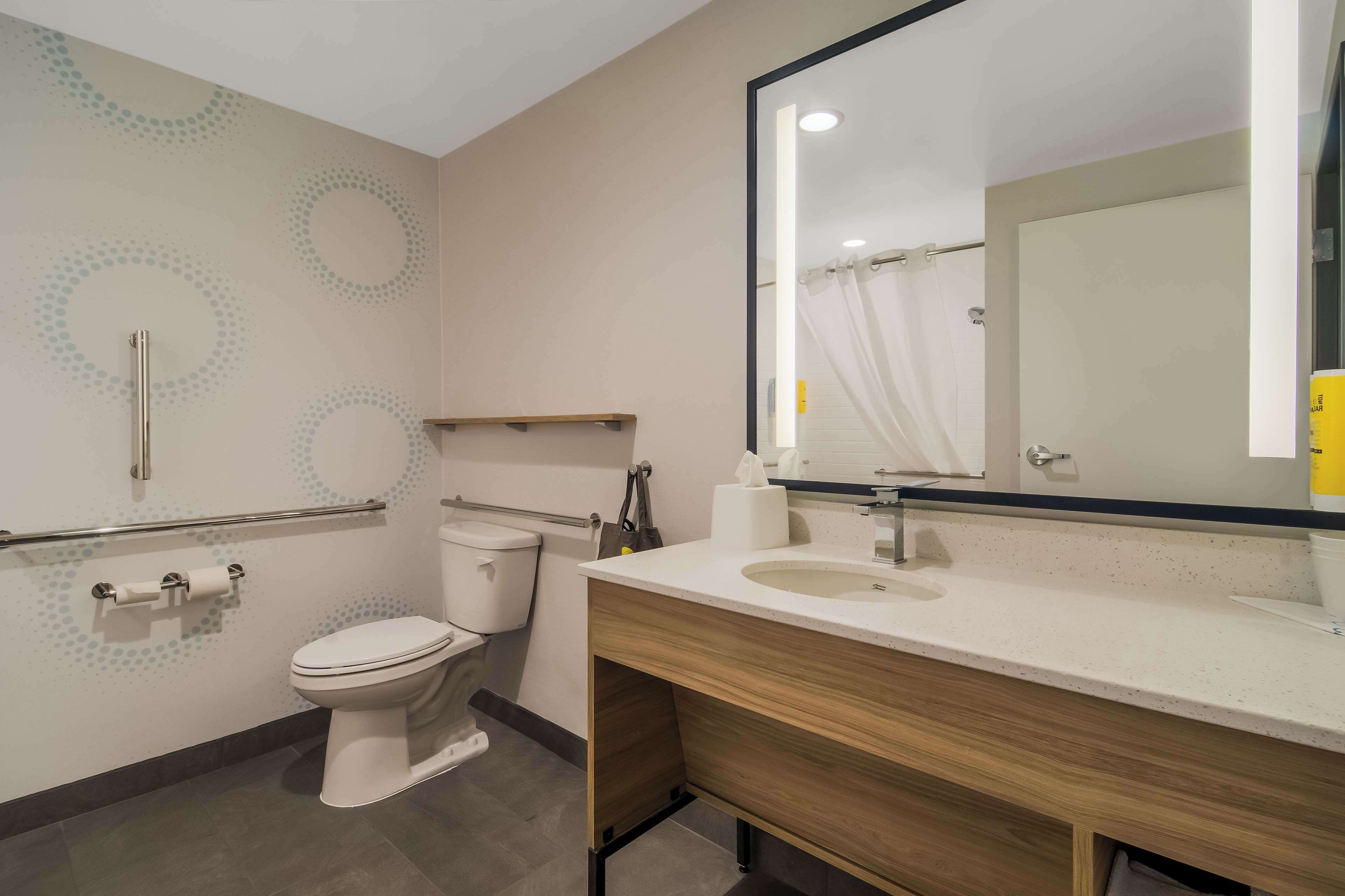 A modern bathroom with a toilet, a sink, and a mirror.
