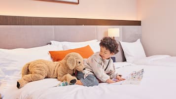 Un niño acostado en una cama con un peluche, leyendo un libro.