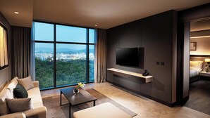 Una habitación de hotel moderna con un ventanal grande, un televisor de pantalla plana, un sofá, una mesita de centro y una cama.