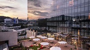 A rooftop terrace with outdoor seating and umbrellas, surrounded by modern buildings.