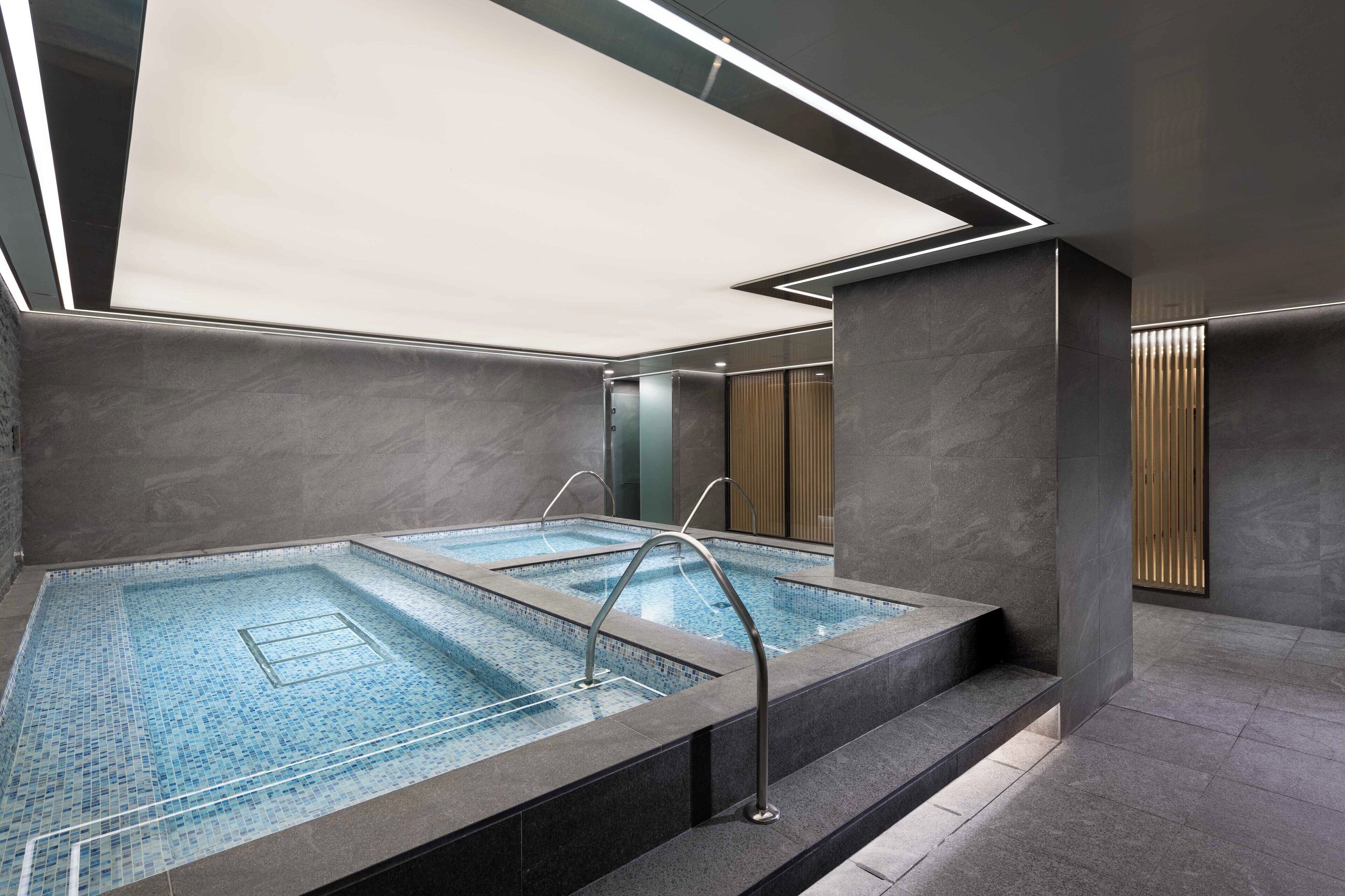 Piscina interior moderna con agua cristalina, estructura de vidrio y diseño minimalista.
