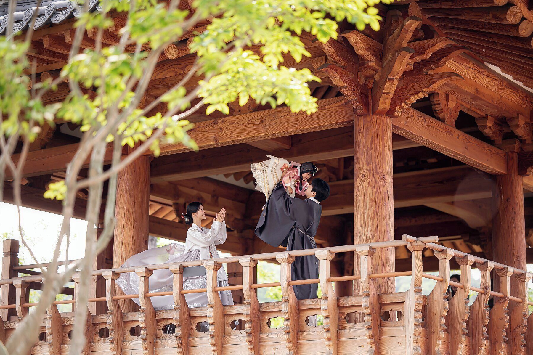 A wooden gazebo with intricate carvings and a wooden railing.