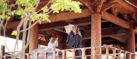 A wooden gazebo with intricate carvings and a wooden railing.