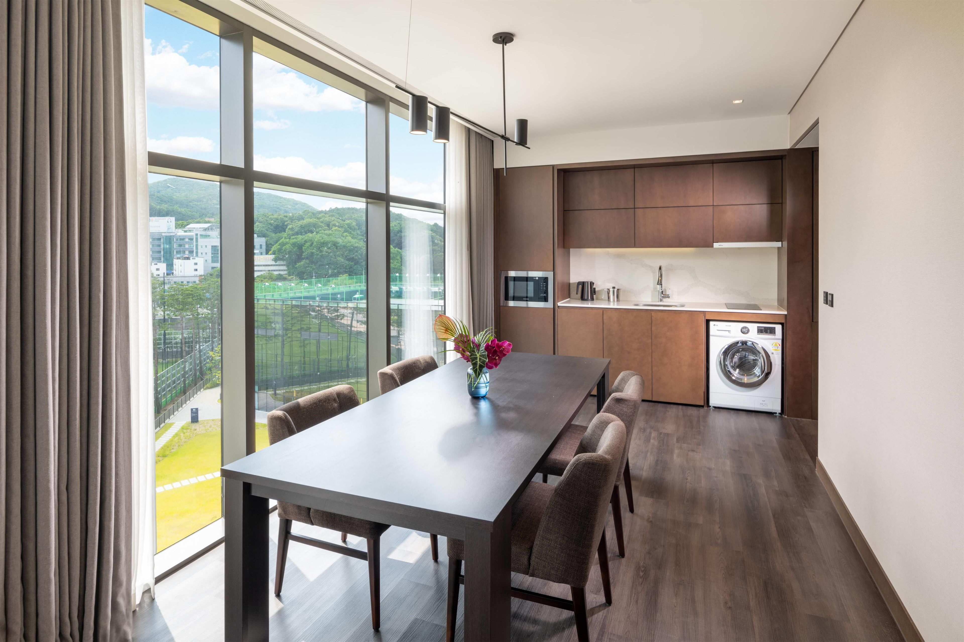 Una cocina moderna con un ventanal grande, una mesa de comedor y una lavadora.
