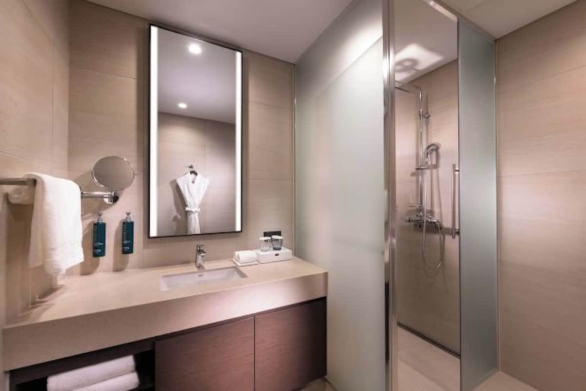 A modern bathroom with a large mirror, a sink, and a glass-enclosed shower.