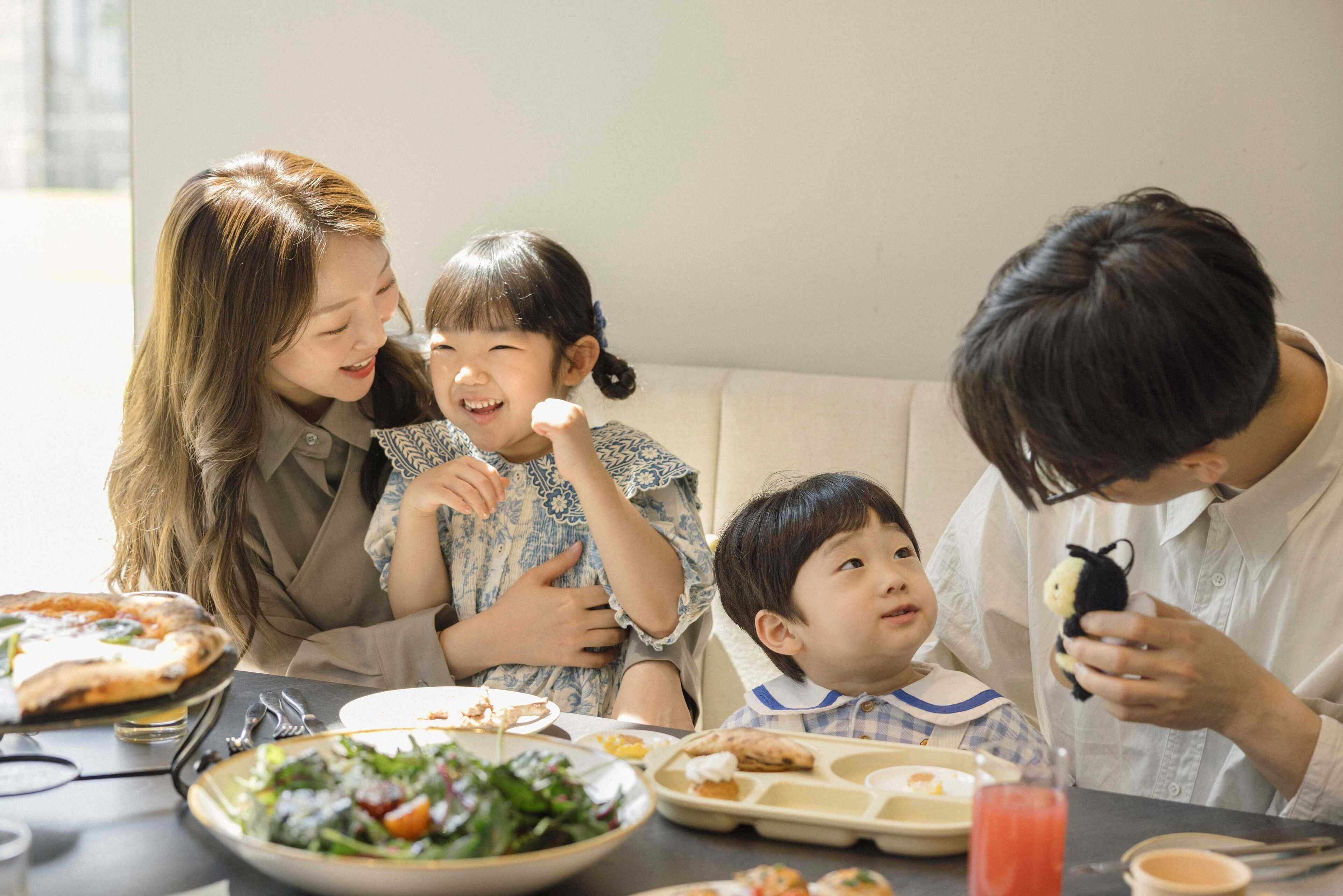 A family dining at a table with various dishes, including pizza and salad.