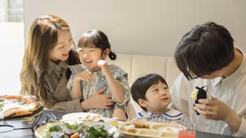 A family dining at a table with various dishes, including pizza and salad.