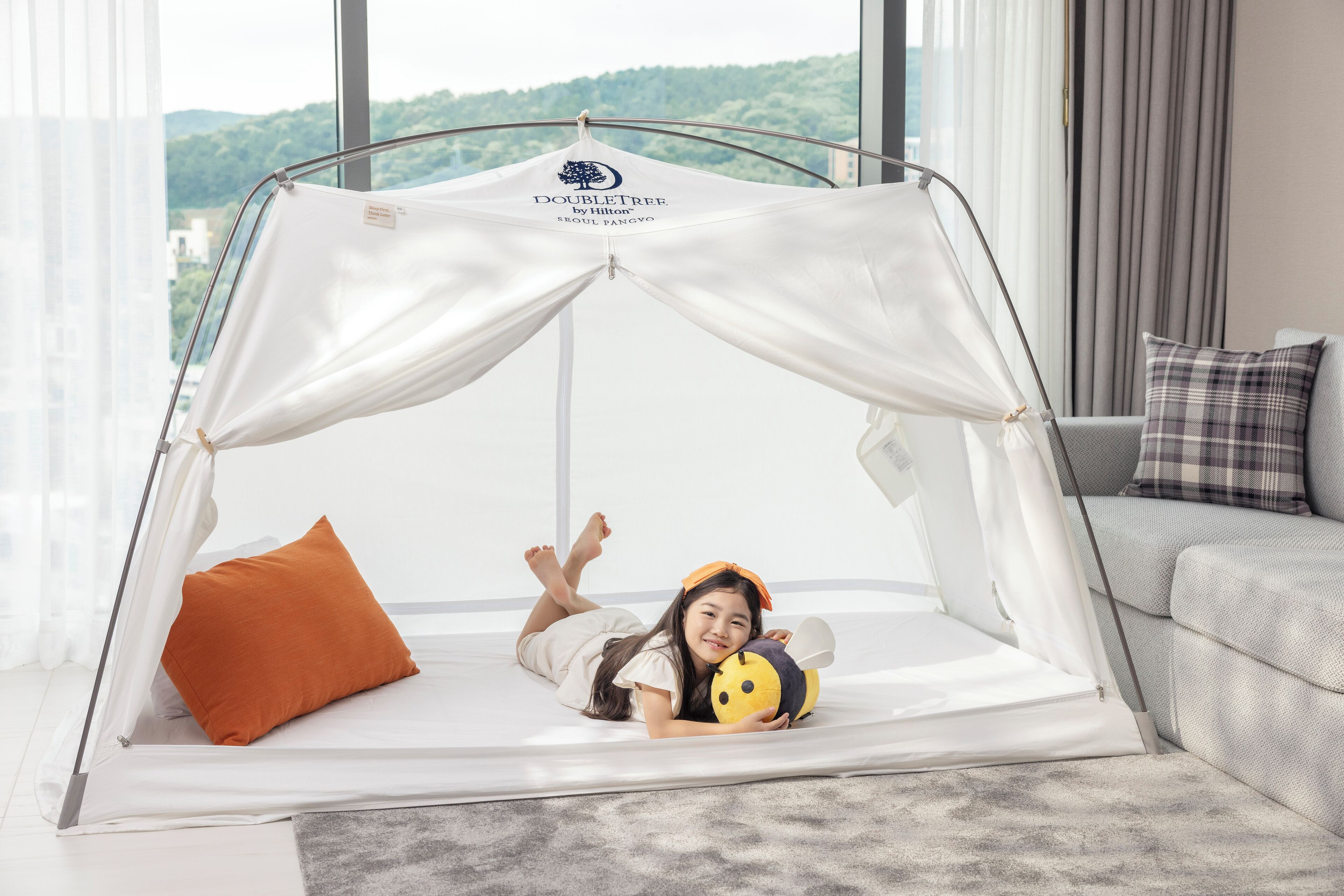A tented sleeping area with a view of a green landscape.