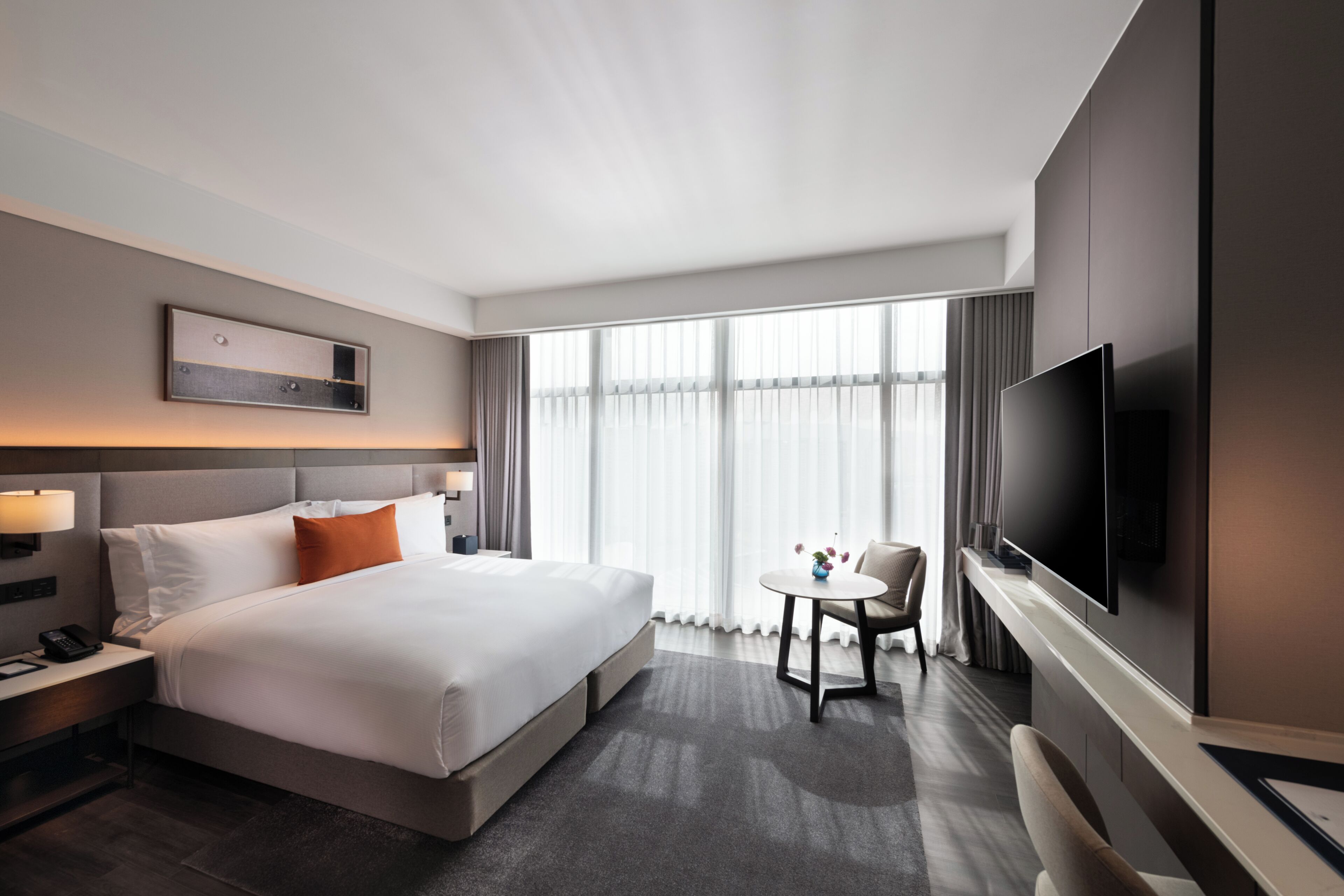 Una habitación de hotel con una cama grande, televisión, una mesita y una silla.