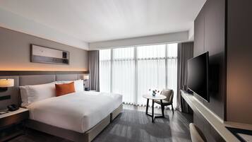 Una habitación de hotel con una cama grande, televisión, una mesita y una silla.