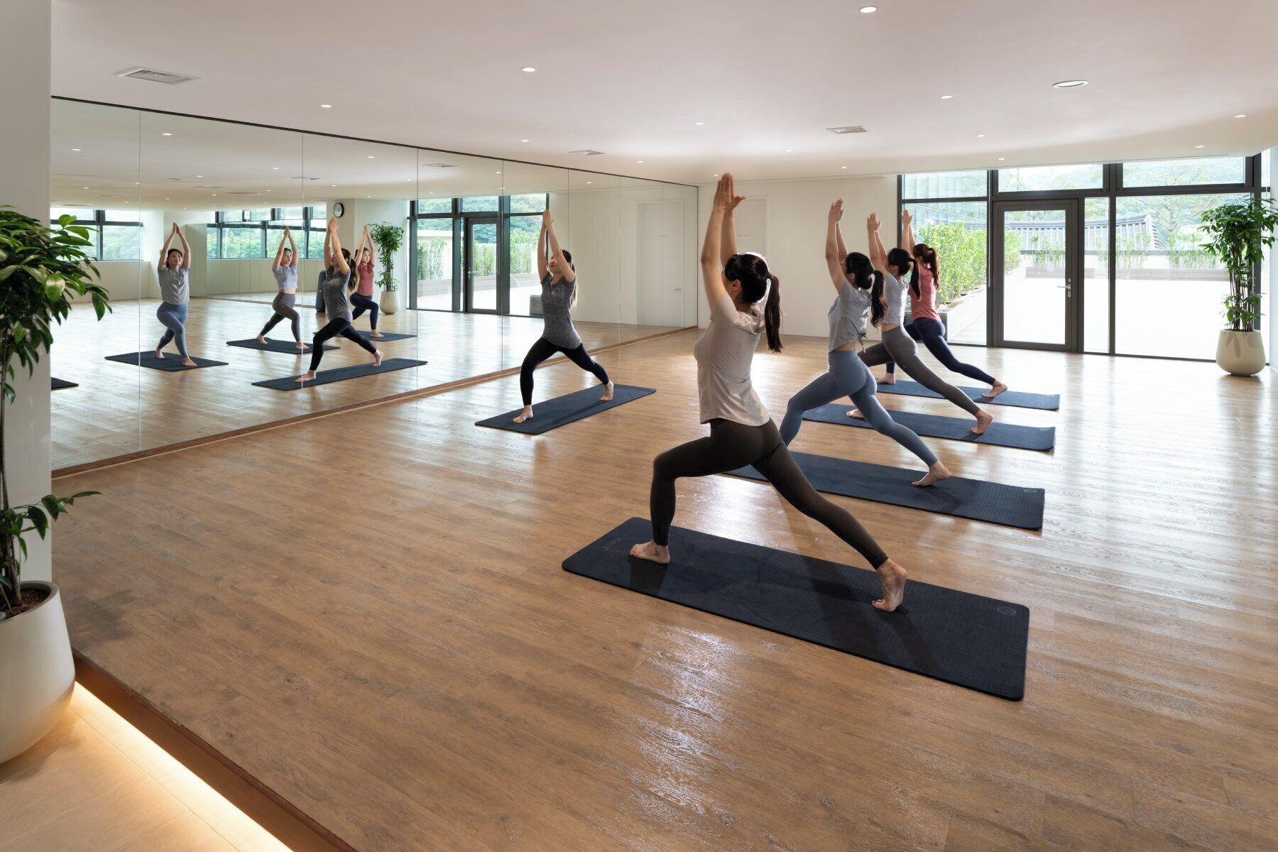 A spacious yoga studio with large windows and wooden floors.