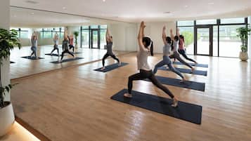 A spacious yoga studio with large windows and wooden floors.