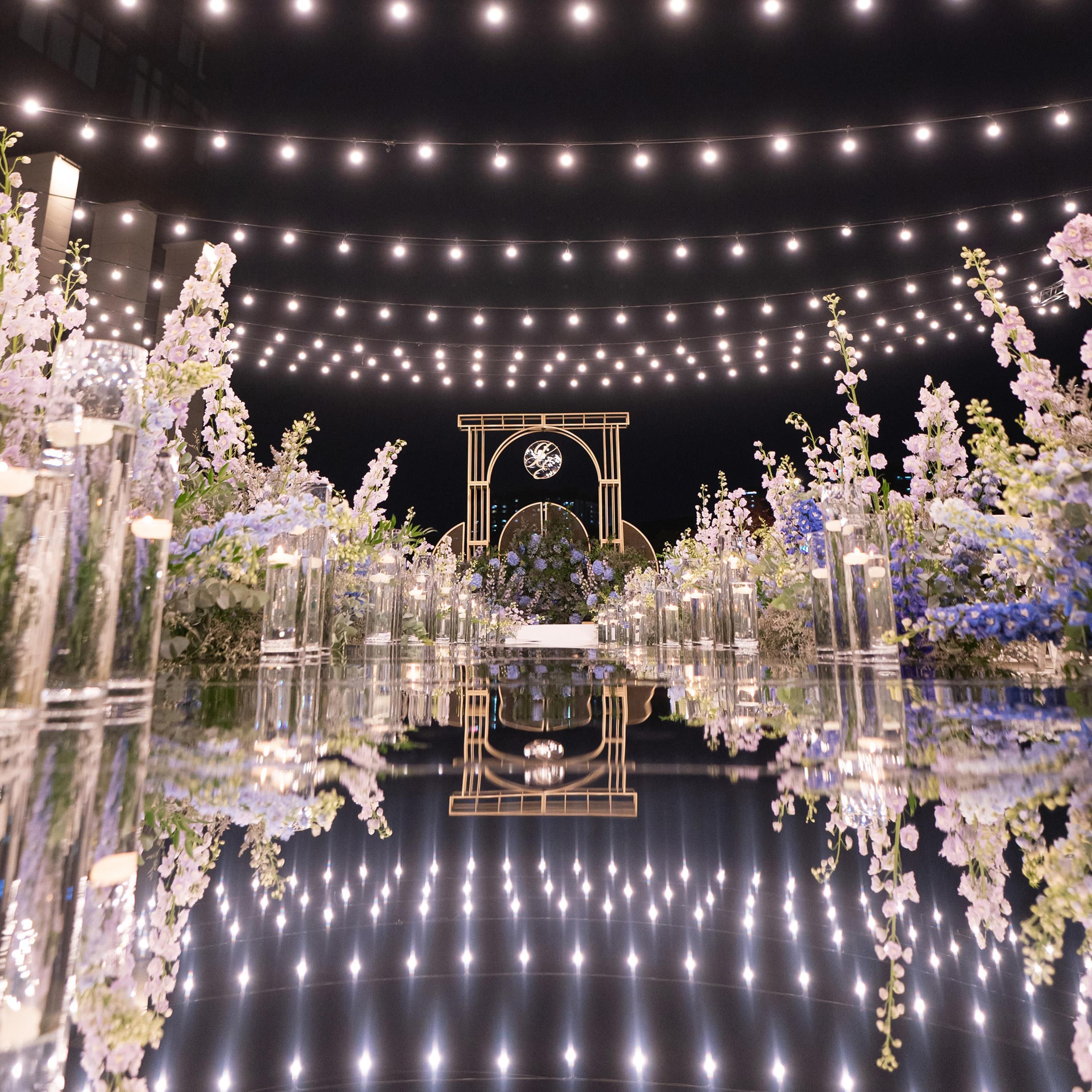 Un suelo reflectante con un arreglo floral central y luces colgantes.