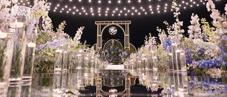 Un suelo reflectante con un arreglo floral central y luces colgantes.