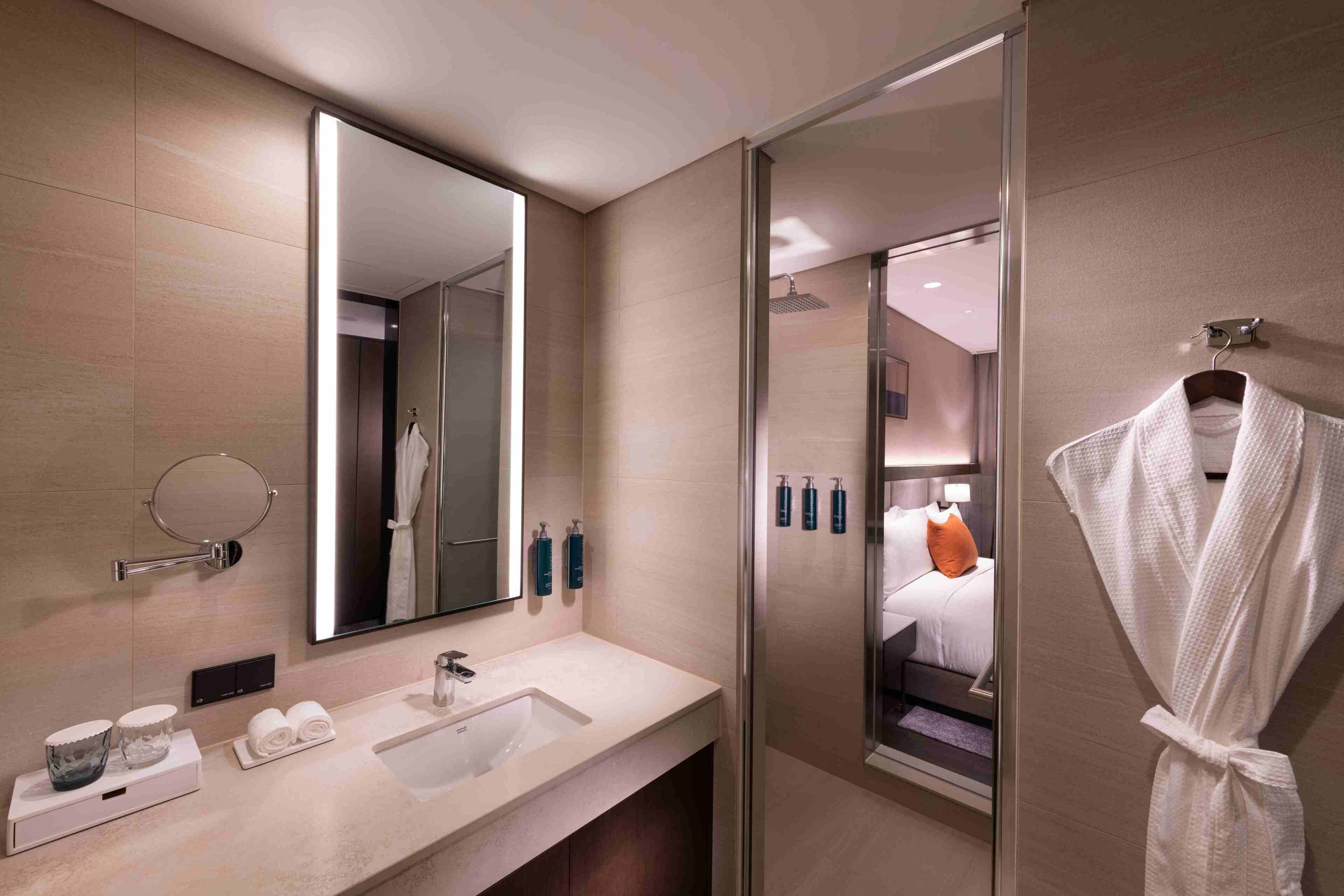 Un baño moderno con un espejo grande, un lavabo y una ducha con mampara de vidrio.