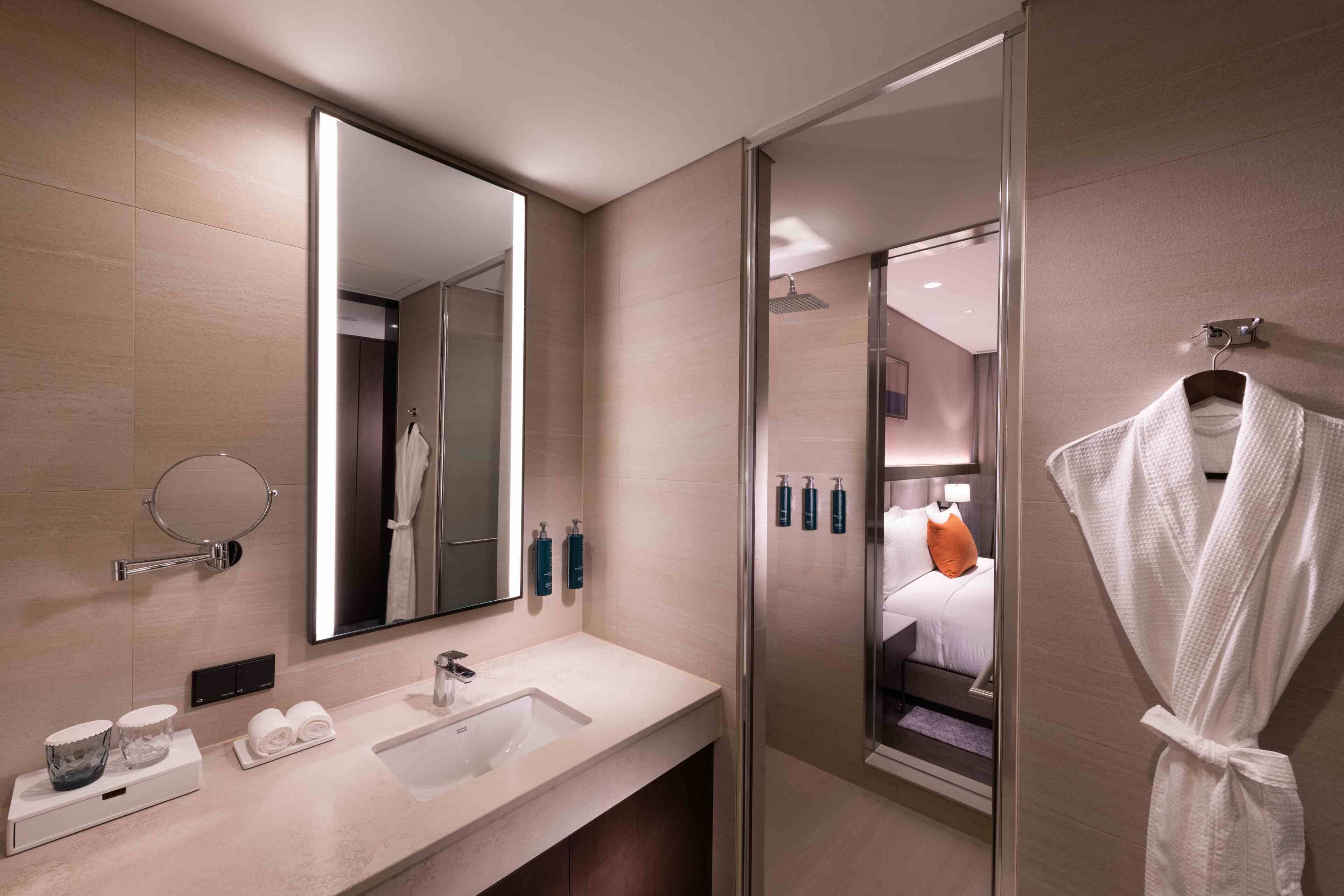 A modern bathroom with a large mirror, a sink, and a glass shower enclosure.